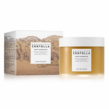 SKIN1004 Madagascar Centella Quick Calming Pad skincare product featuring the outer cardboard box with a desert landscape design next to the clear amber round tub of 70 toning pads.